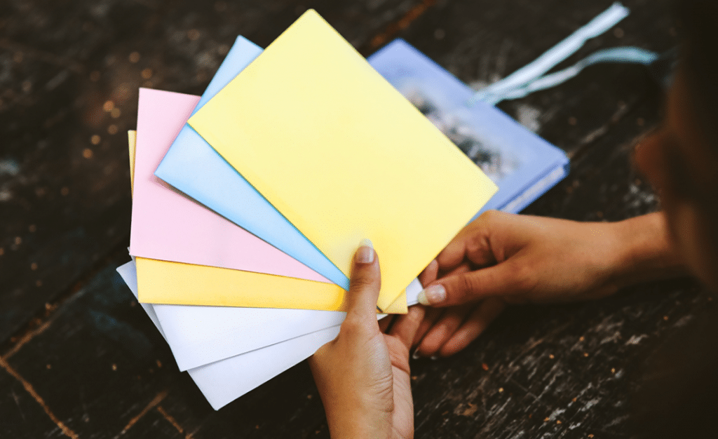 Sparen lernen mit der Umschlagmethode_Hand hält farbige Umschläge