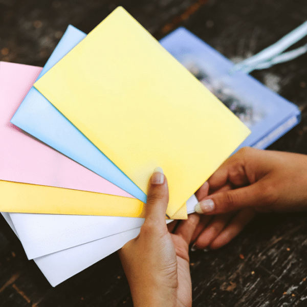 Sparen lernen mit der Umschlagmethode_Hand hält farbige Umschläge